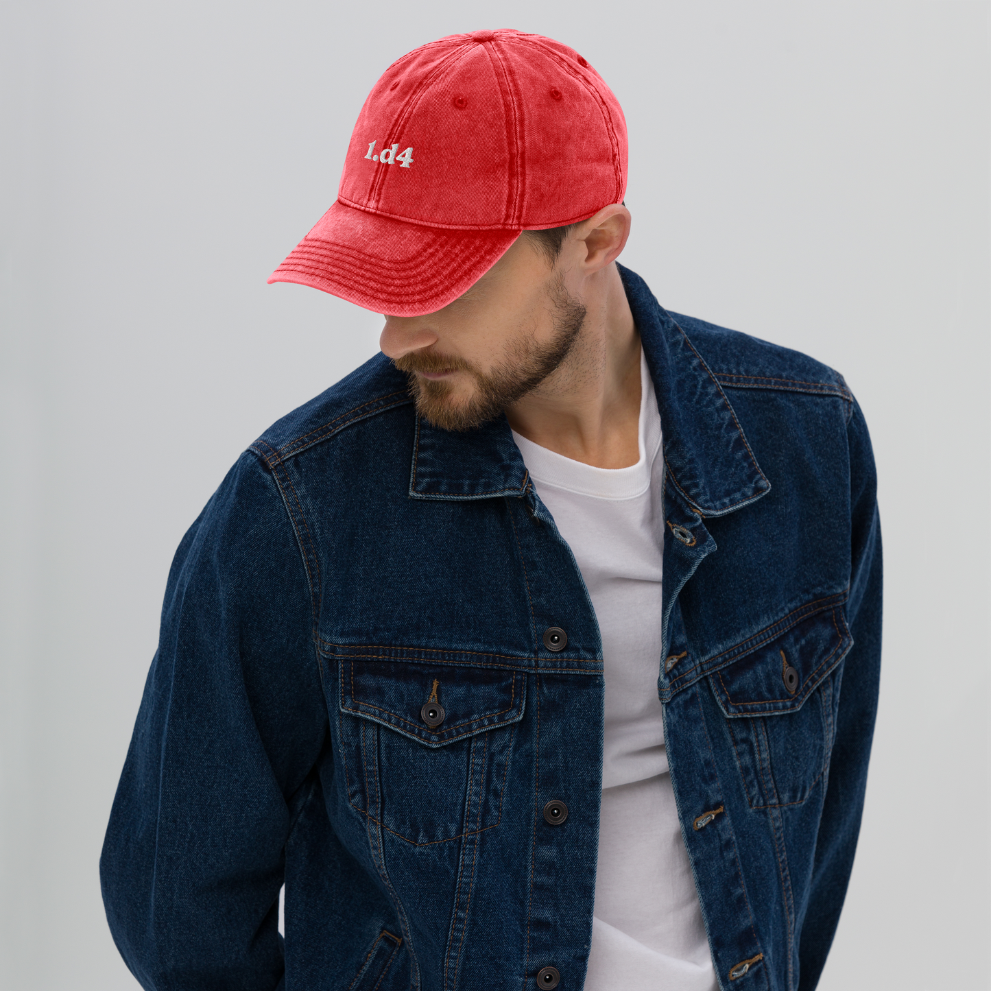 Man wearing a red cap and blue denim jacket on a gray background