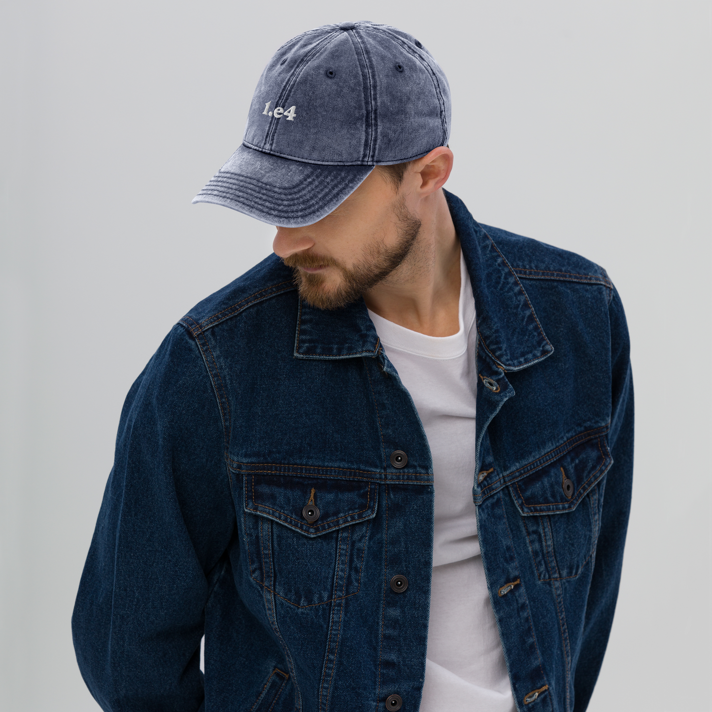 Man wearing a blue denim jacket and cap on a gray background