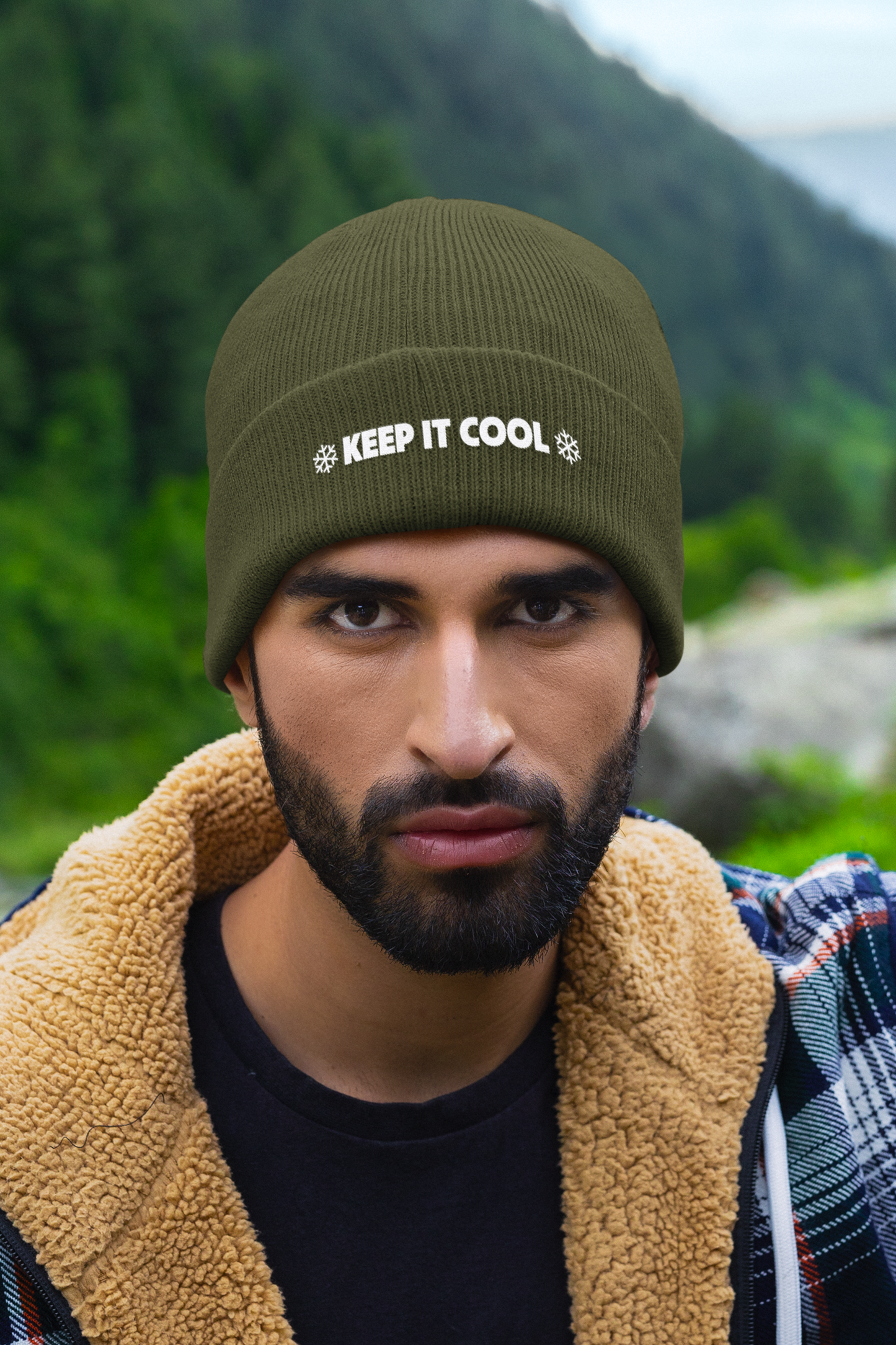 Man wearing a green beanie with 'KEEP IT COOL' text in a natural setting