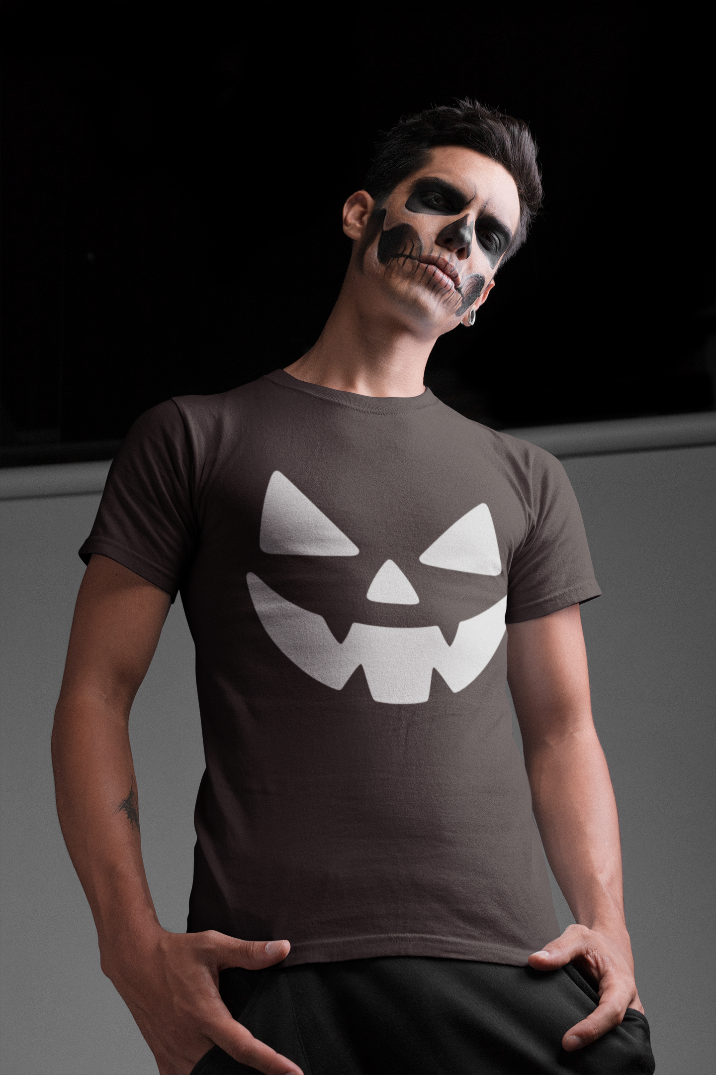 Person wearing a brown t-shirt with a jack-o'-lantern face design against a black background