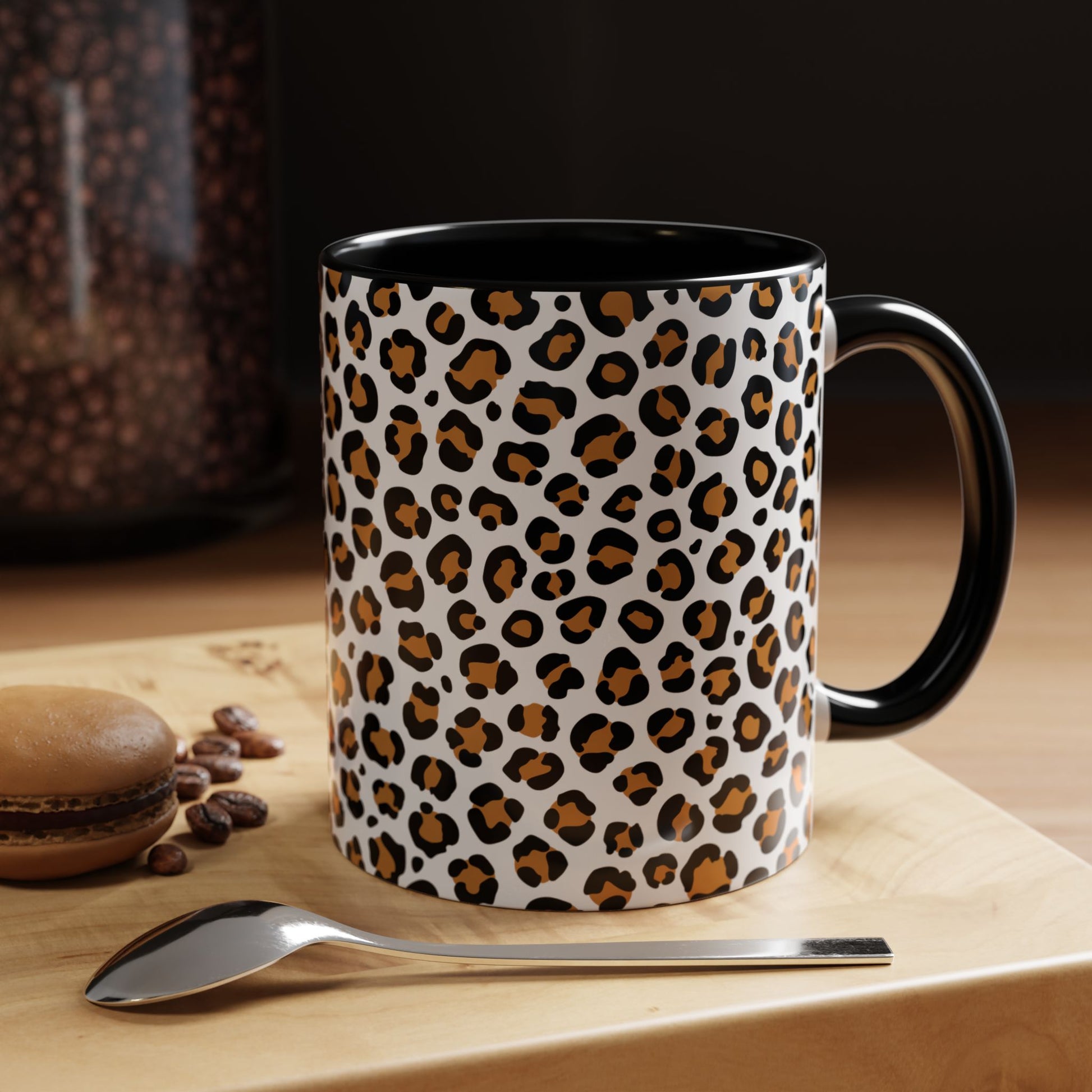 Leopard print mug on a wooden surface with coffee beans and a spoon.