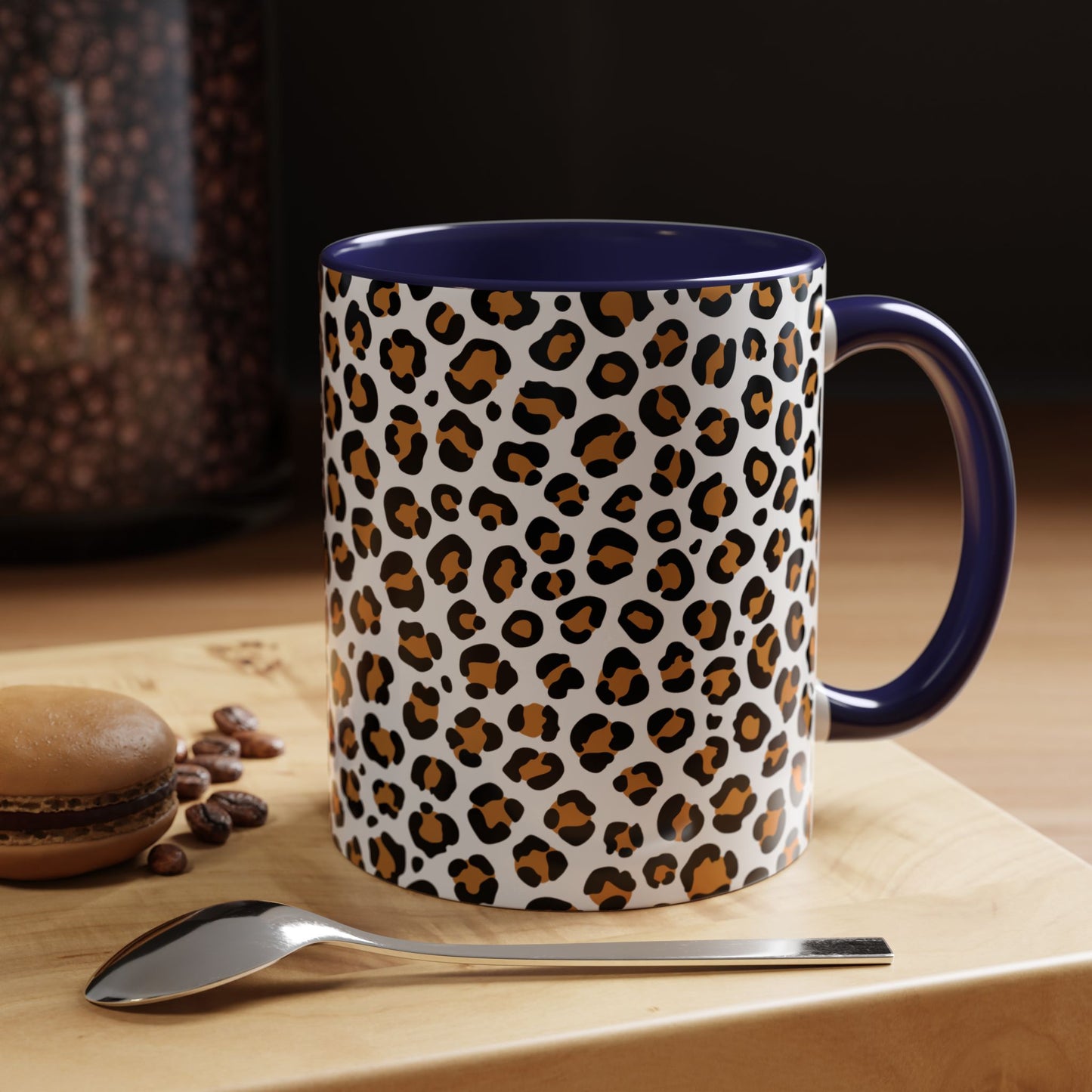 Leopard print mug with blue interior on a wooden surface with coffee beans and a spoon.