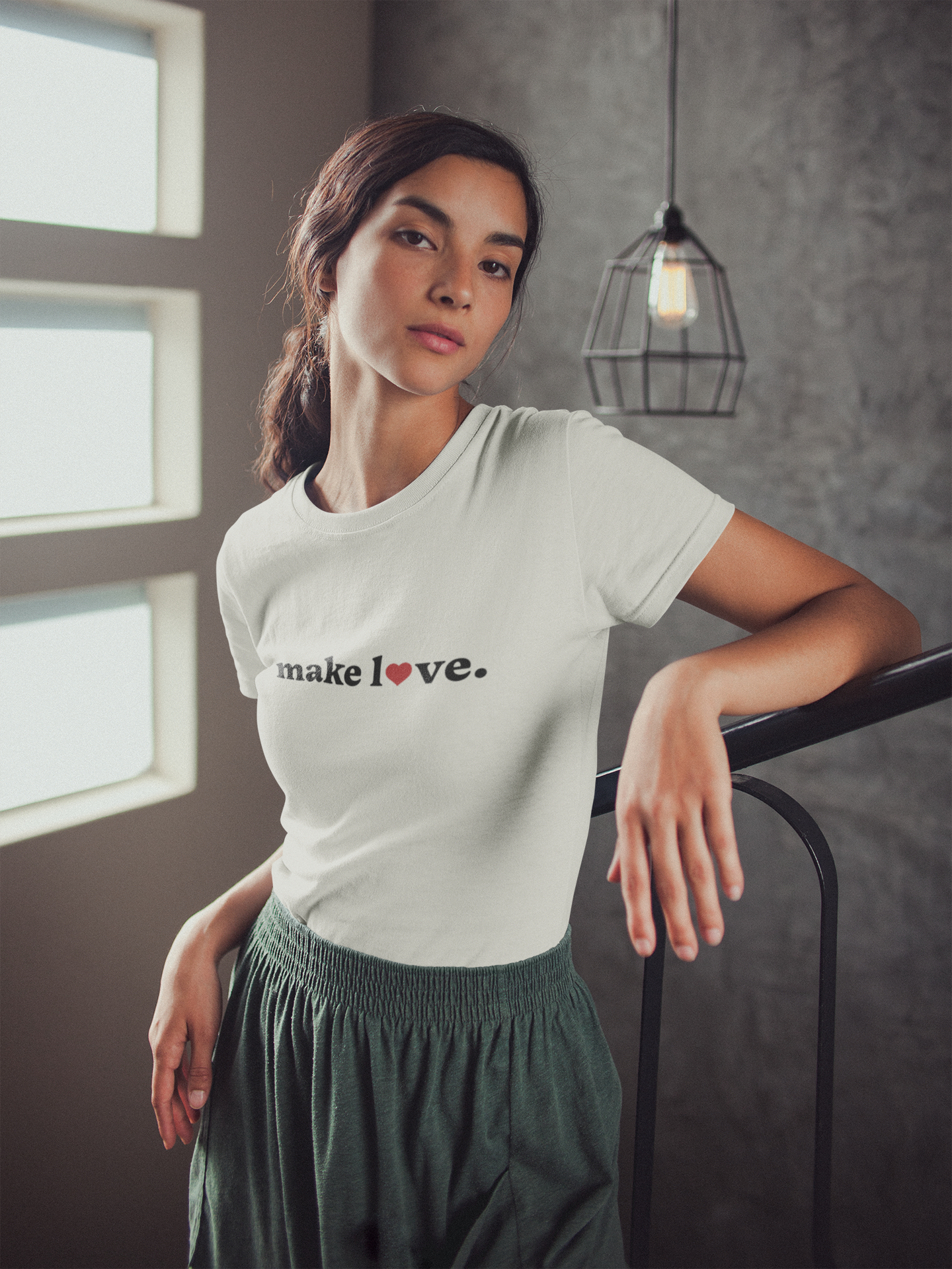 Woman wearing a natural t-shirt with 'make love.' text, standing indoors.