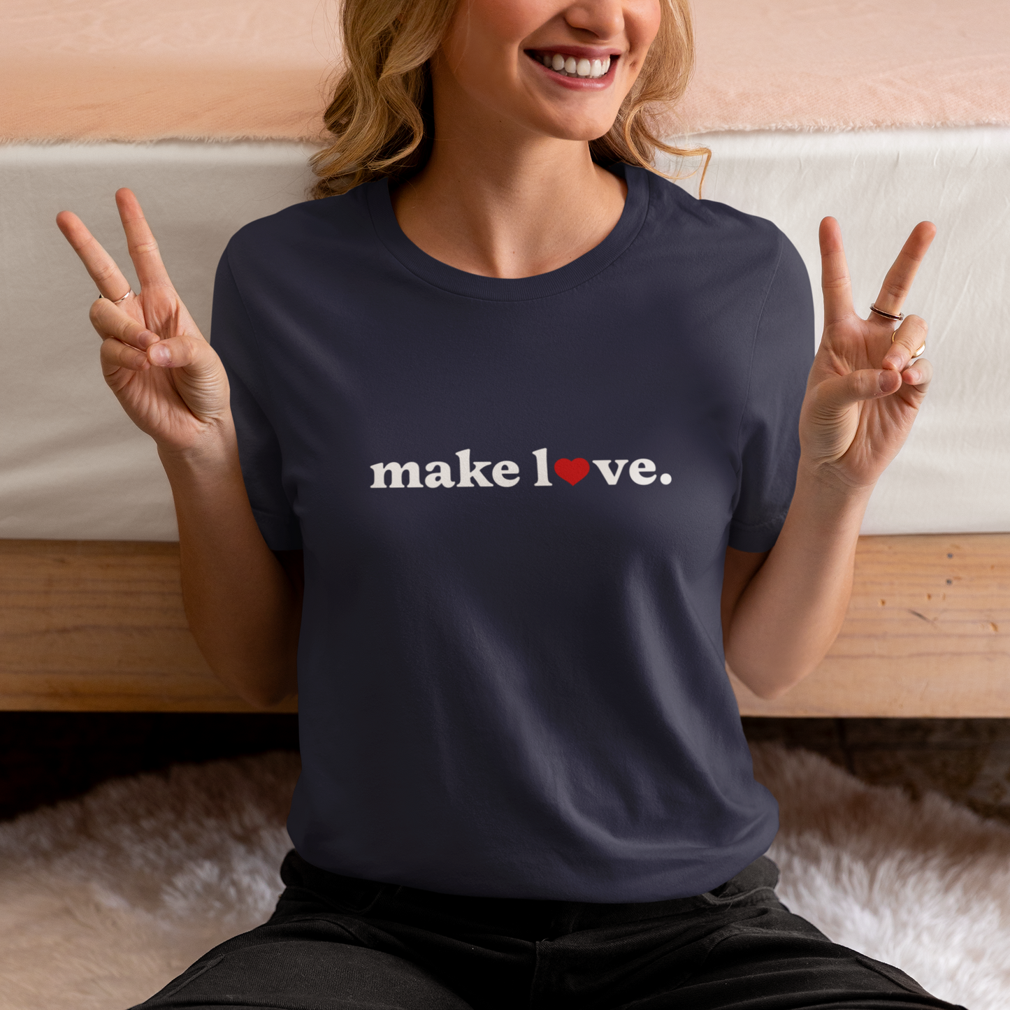 Person wearing a navy blue t-shirt with 'make love.' text, sitting on a couch.