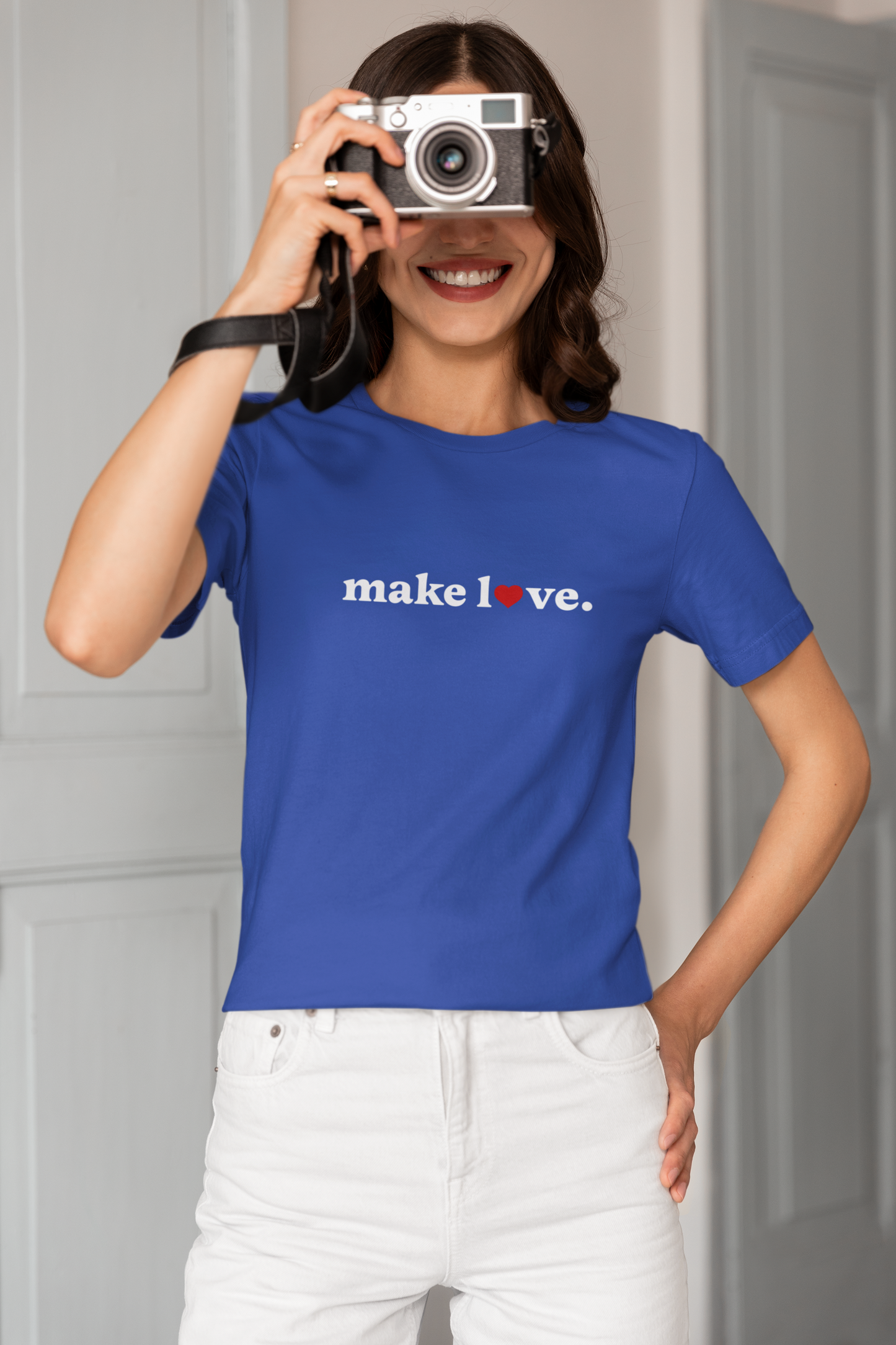 Person wearing a blue t-shirt with 'make love.' text, holding a camera.