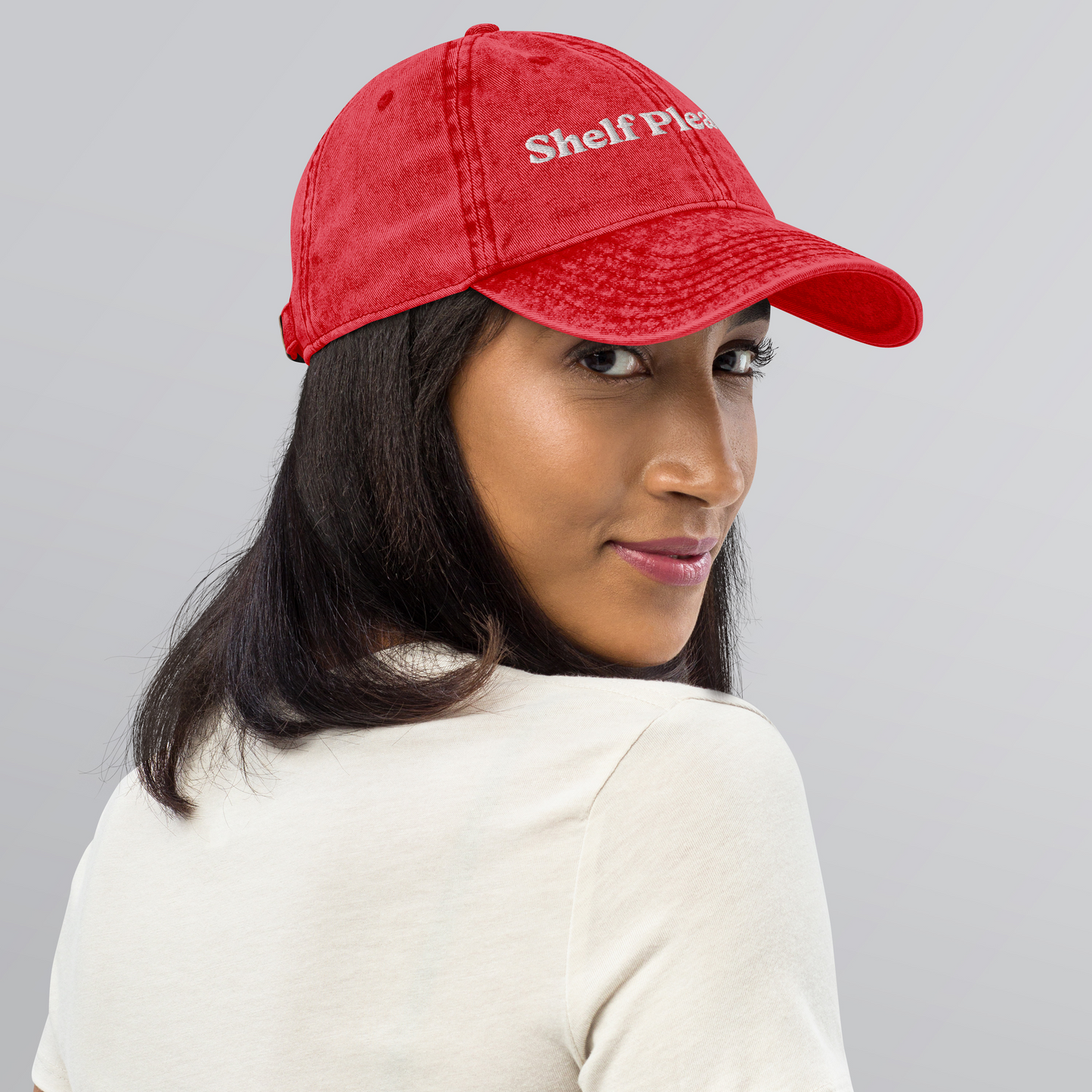 Person wearing a red cap with 'Shelf Plea' text on a gray background