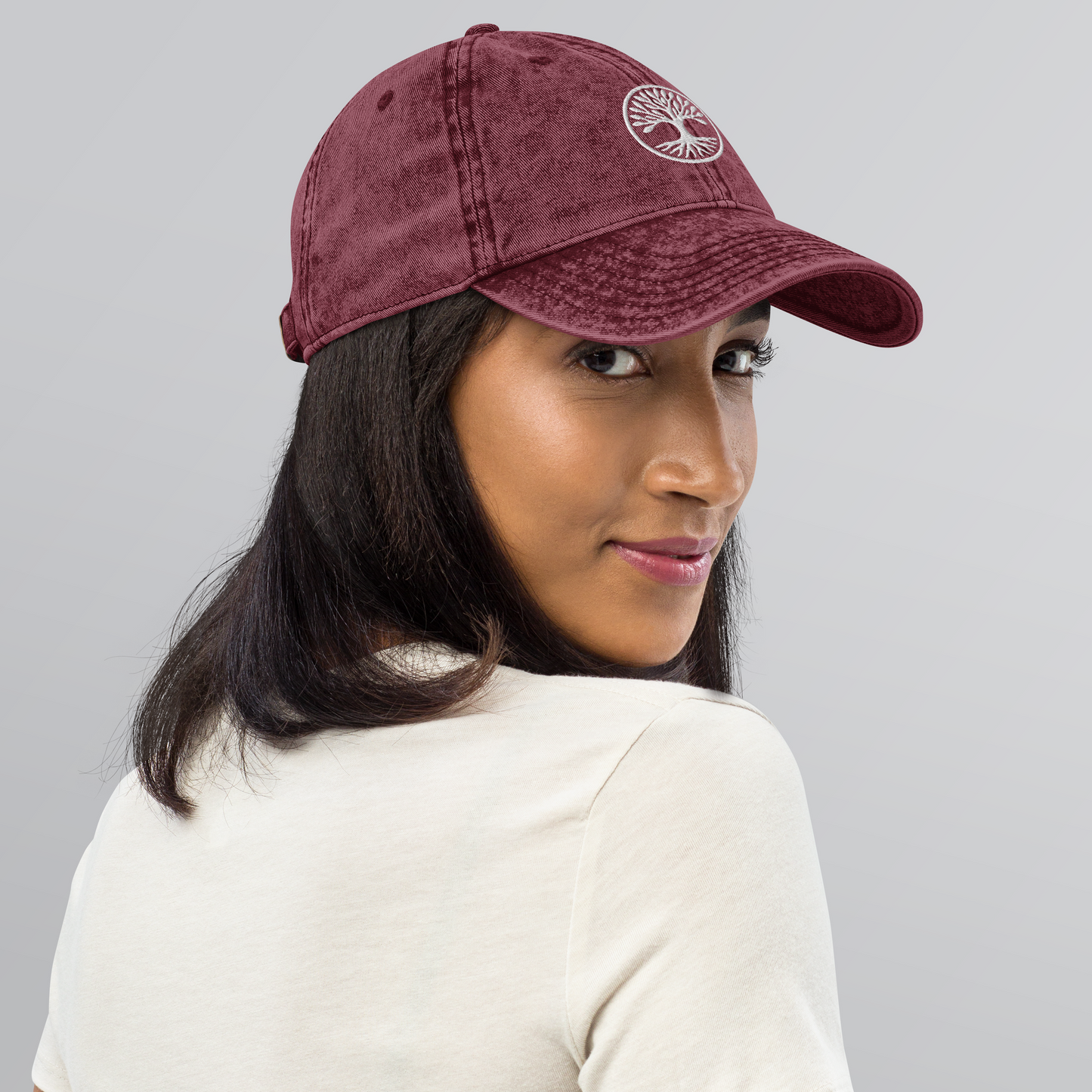 Person wearing a maroon cap with a logo on a gray background