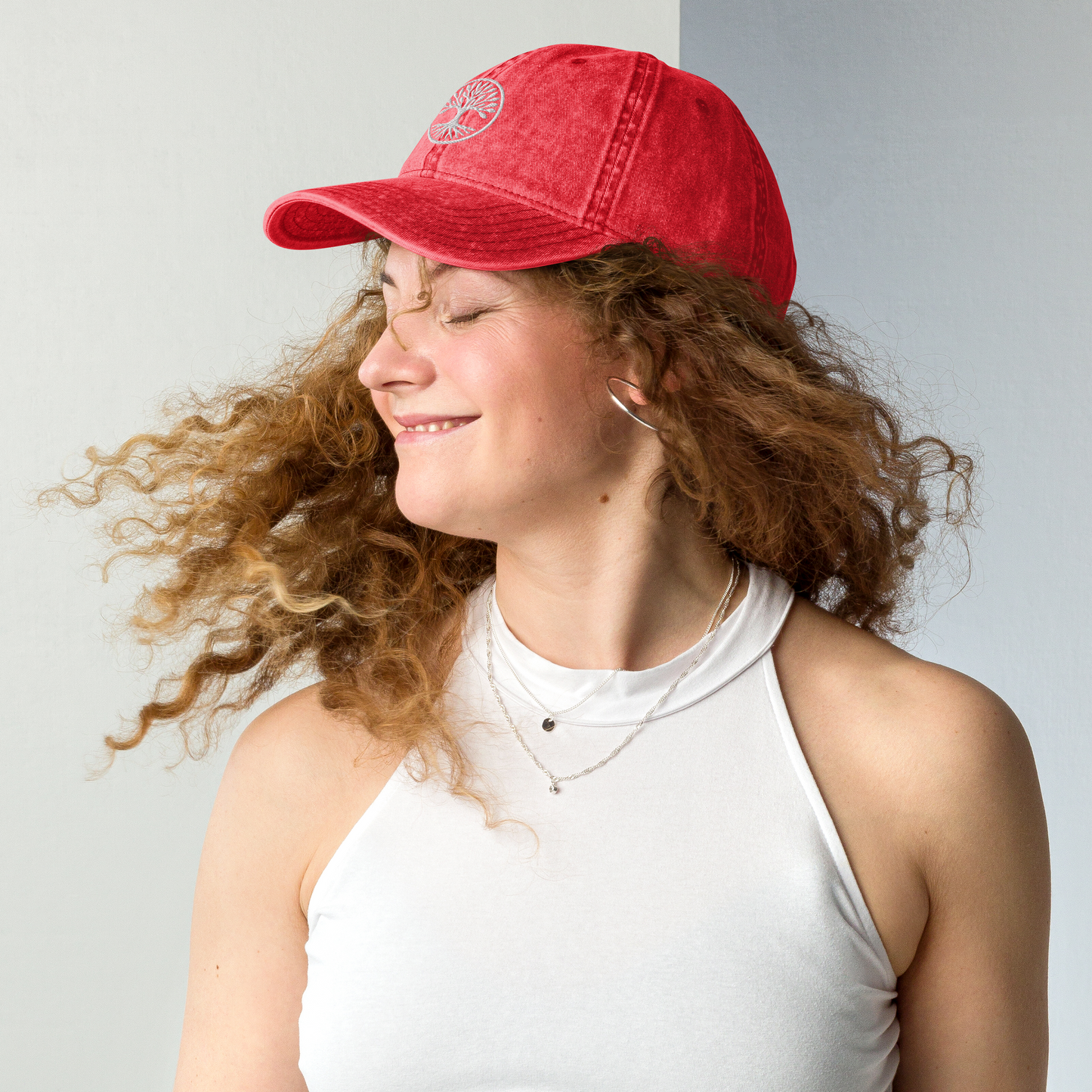 Person wearing a red cap with a logo on a plain background