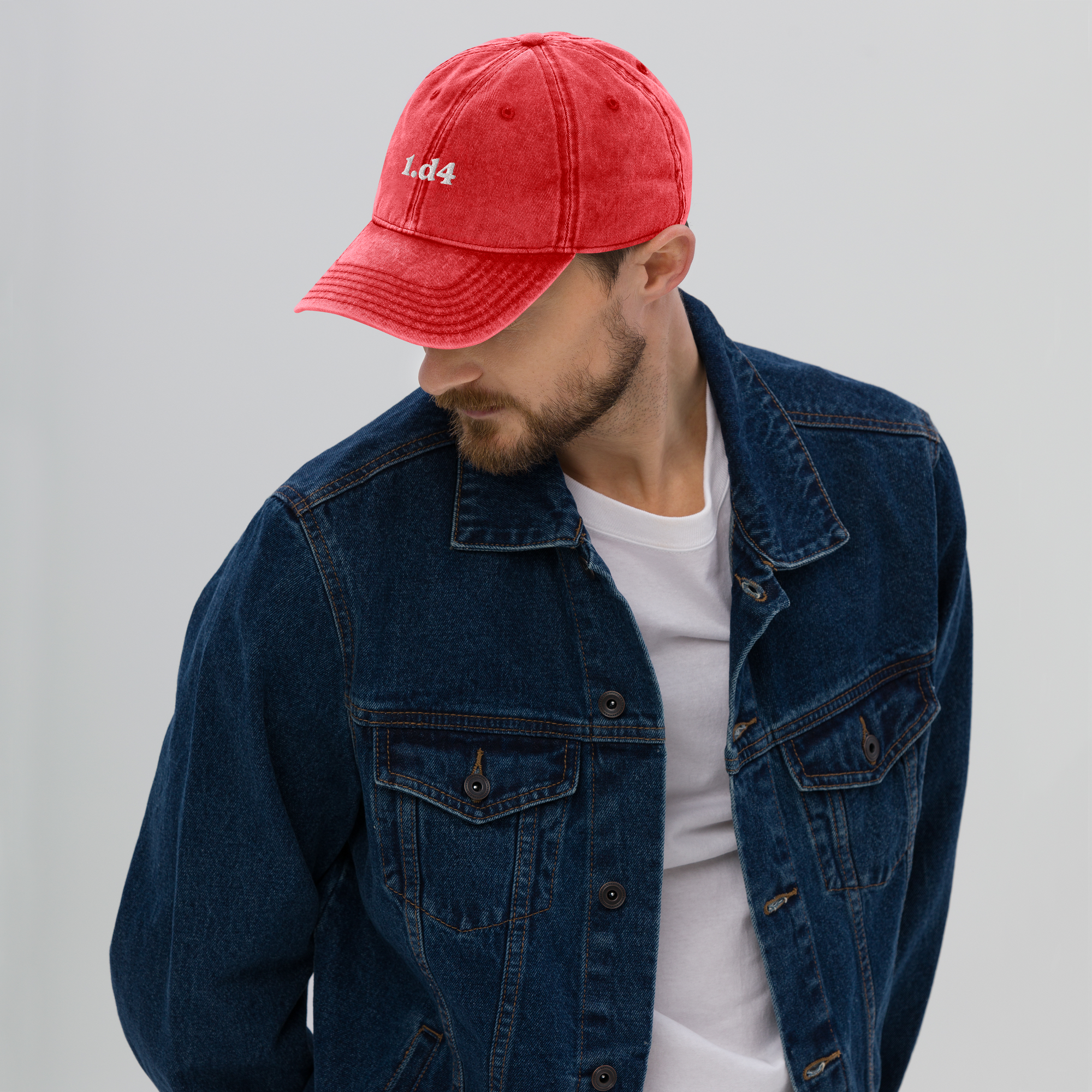 Man wearing a red cap and blue denim jacket on a gray background