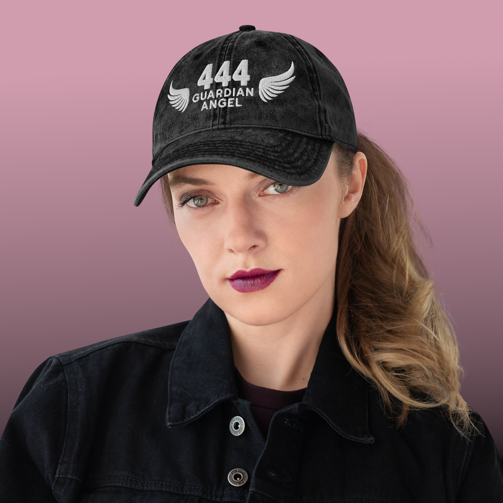Person wearing a black cap with '444 Guardian Angel' text against a pink background