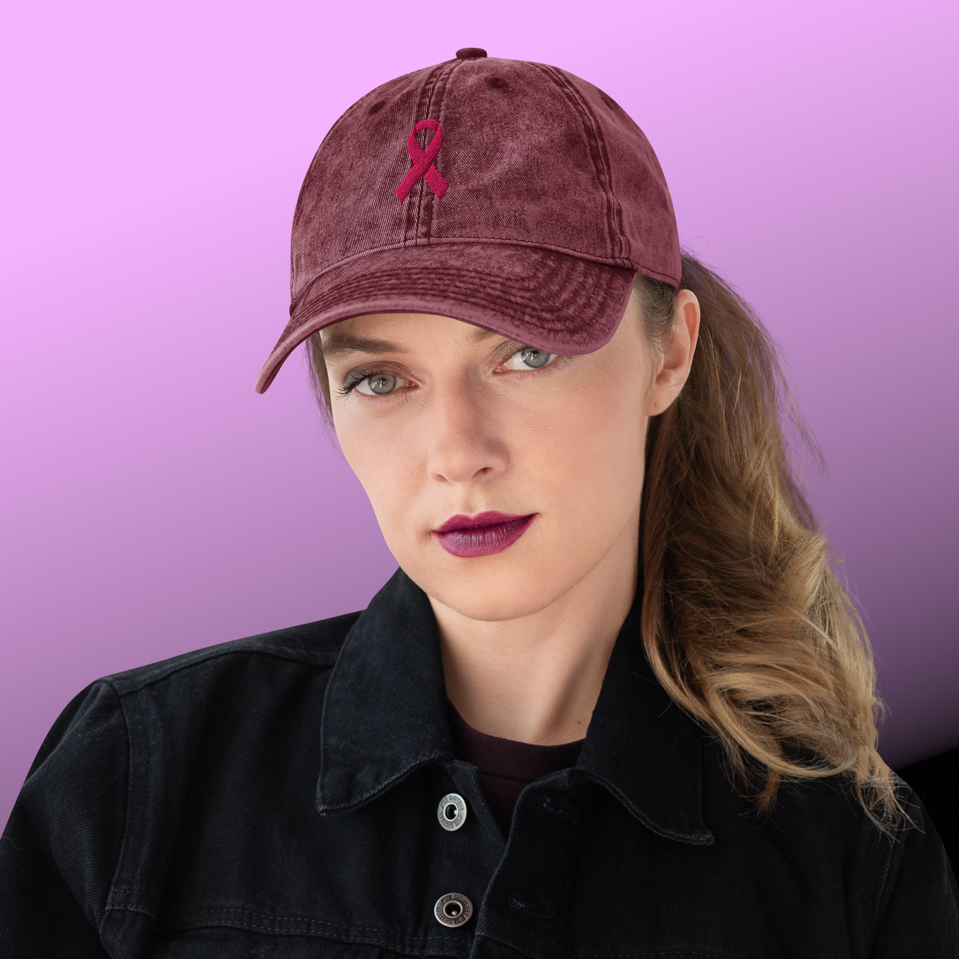 Person wearing a maroon cap with a pink ribbon on a purple background