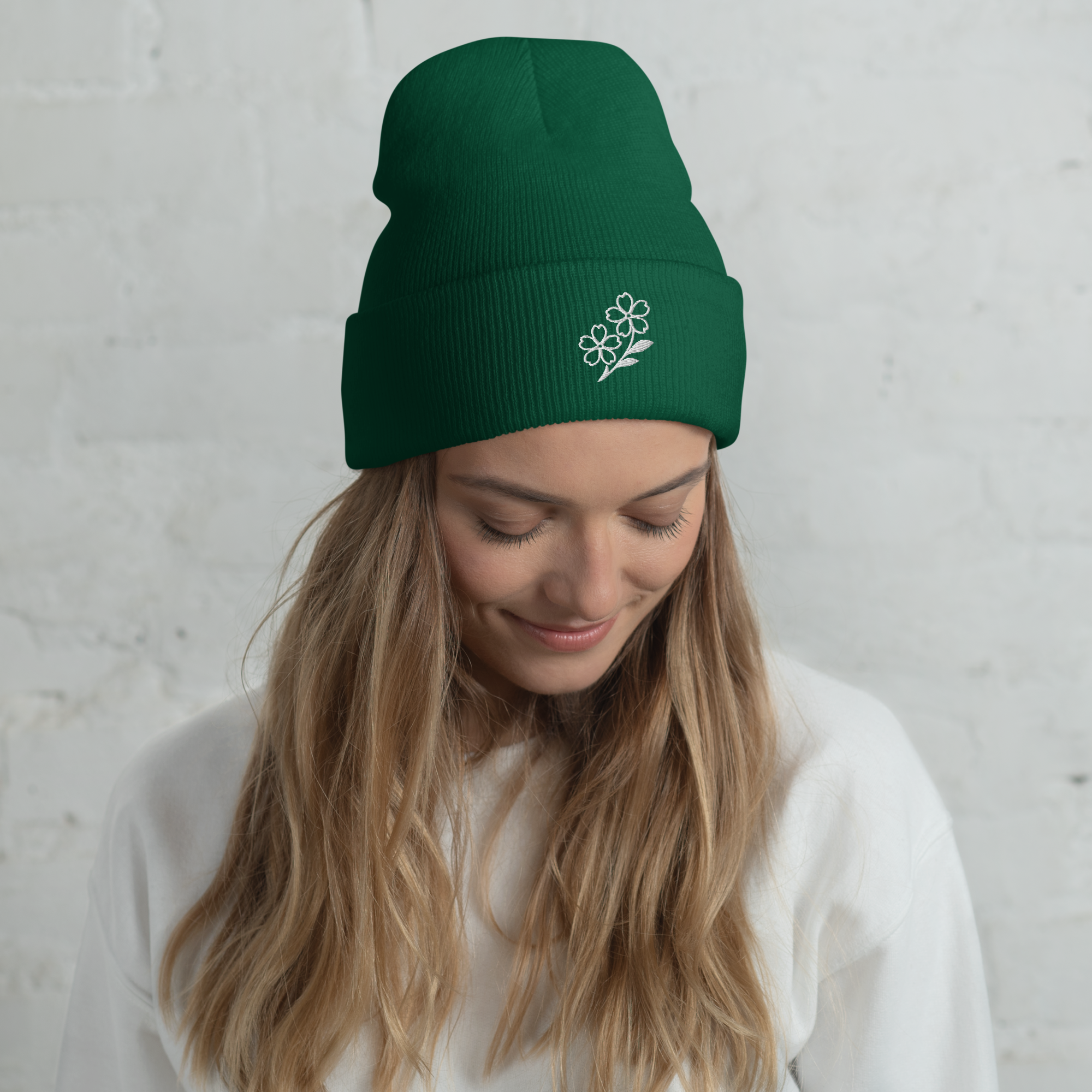 Woman wearing a green beanie with a floral design against a light gray background