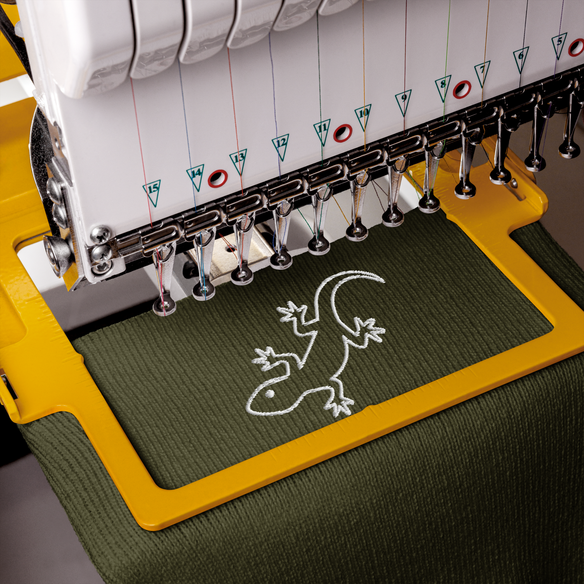 Embroidery machine with a lizard design on green fabric