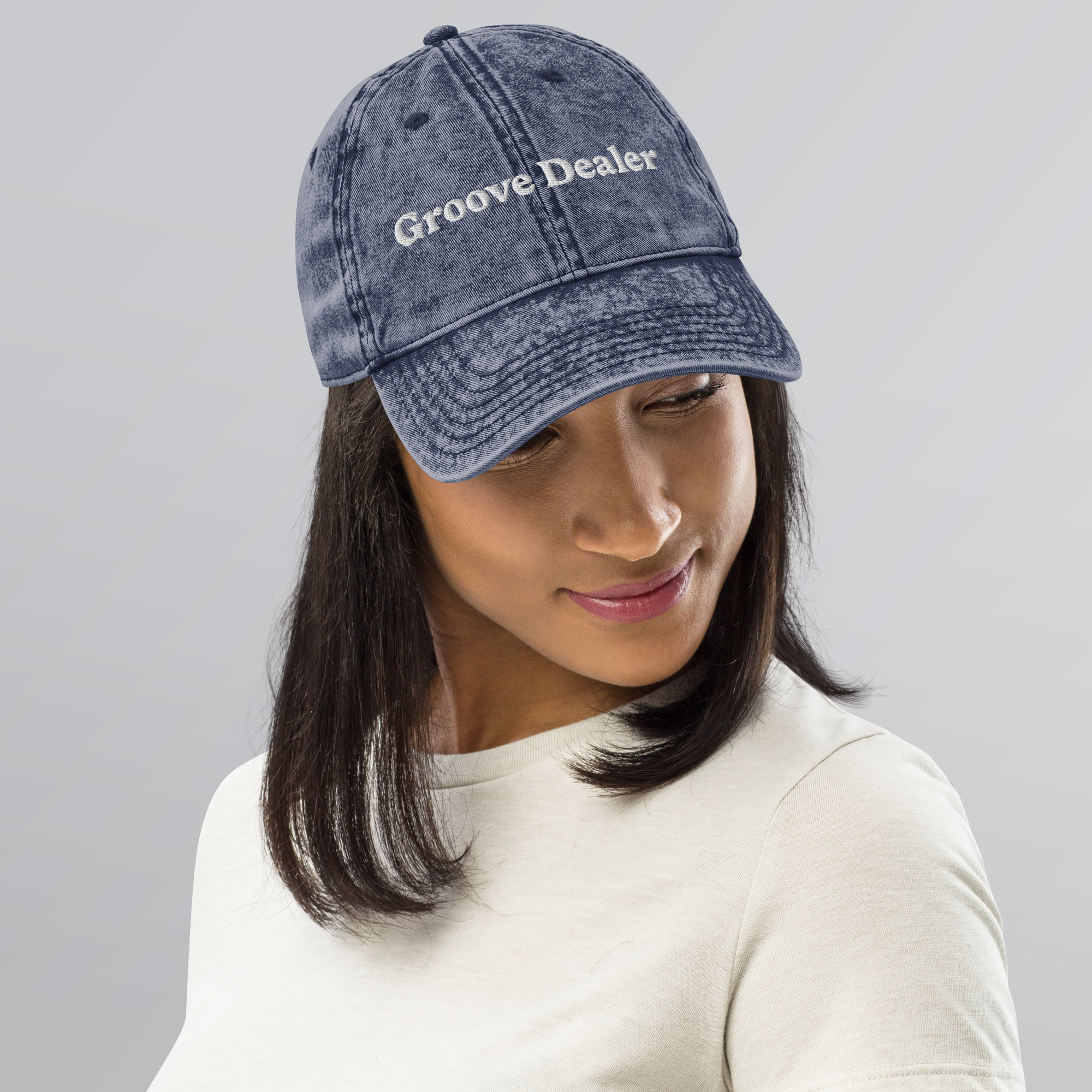Person wearing a denim cap with 'Groove Dealer' text on a gray background