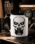 White mug with black skull design on a dark surface with music equipment in the background
