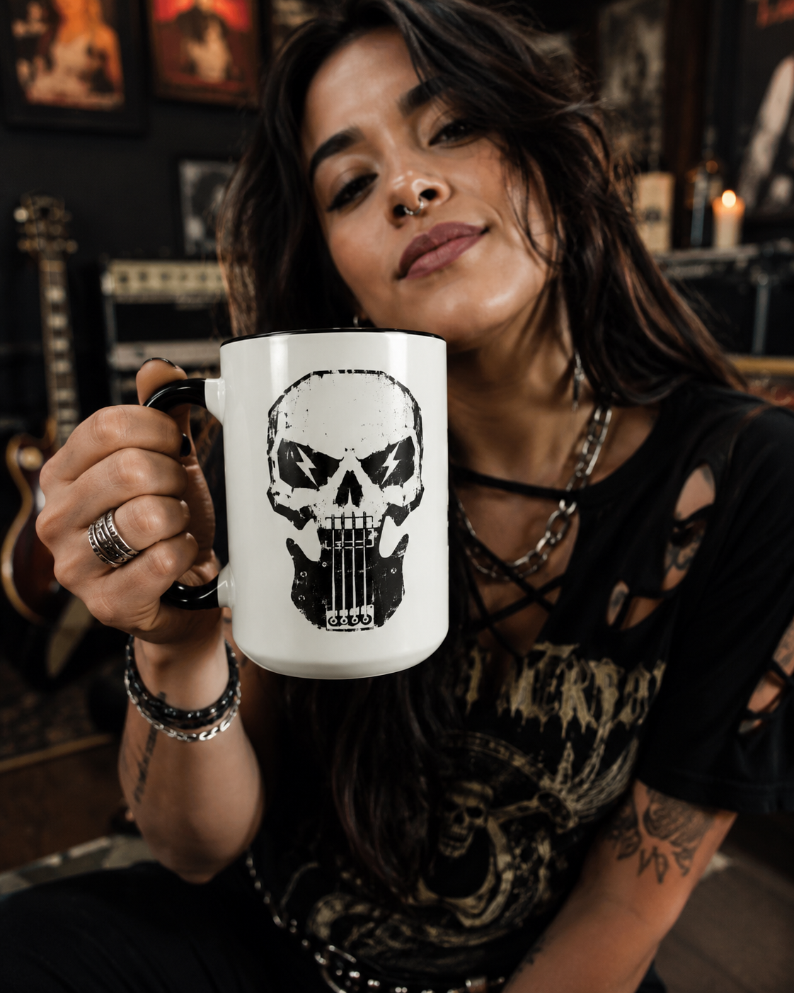 Woman holding a white mug with a skull and guitar design in a dimly lit room.