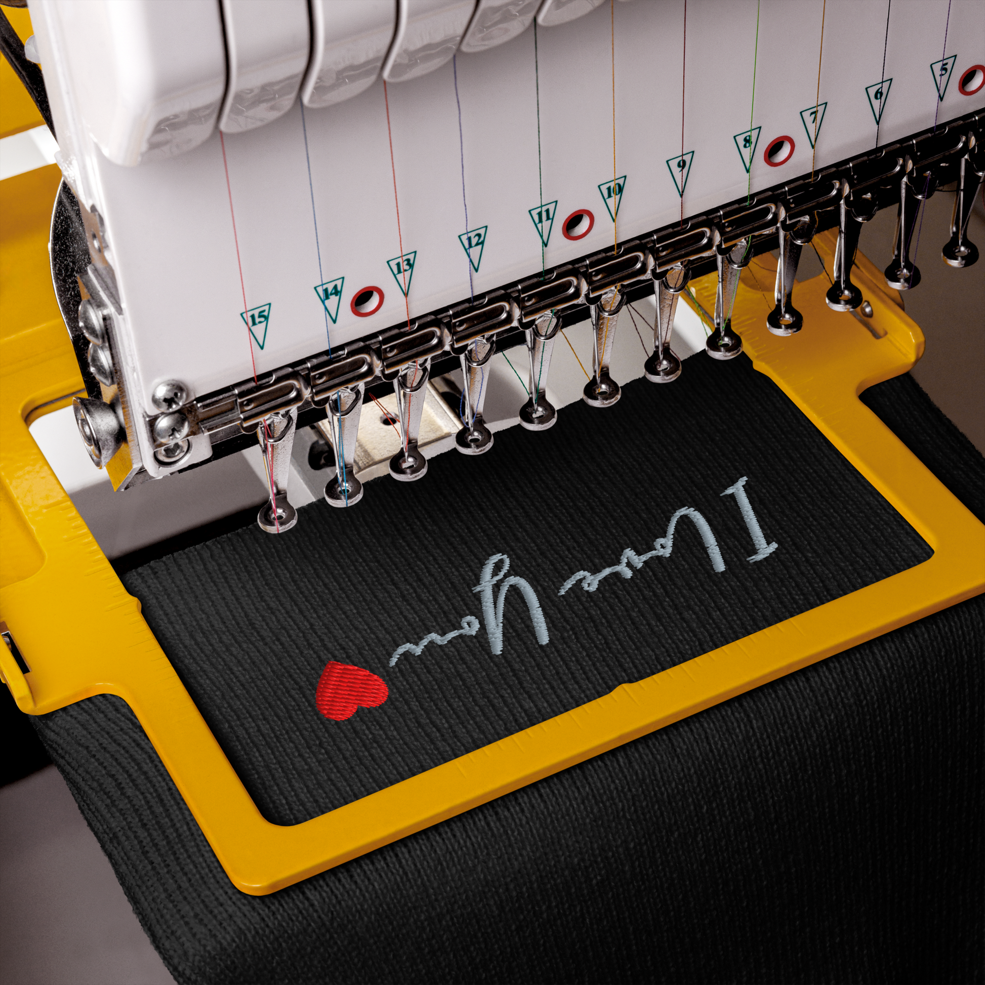 Embroidery machine with 'I love you' and heart design on a black mat