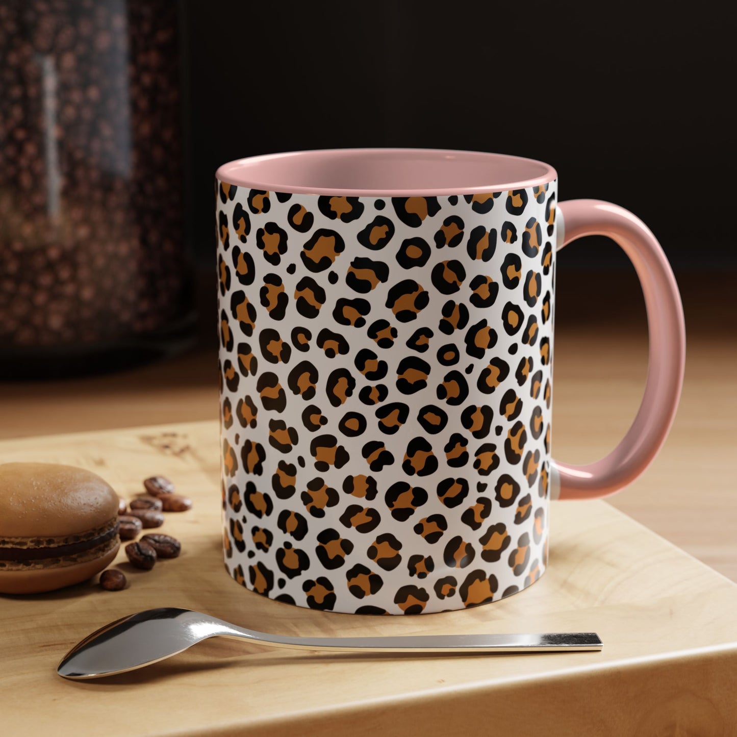 Mug with leopard print pattern on a wooden surface with coffee beans and a spoon.