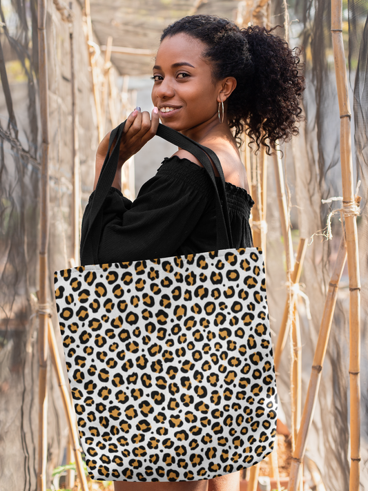 Woman holding a leopard print tote bag in front of a natural background