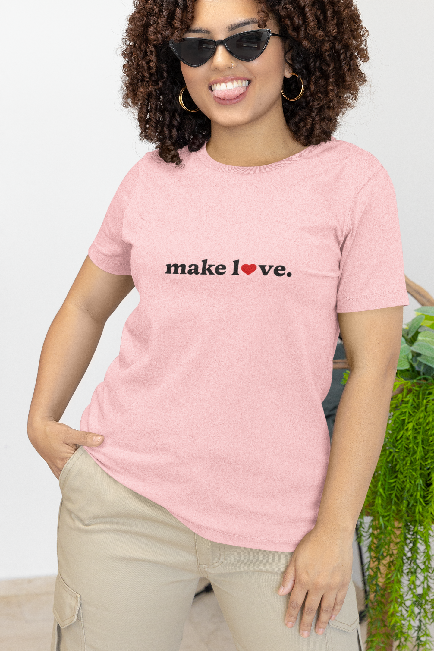 Person wearing a pink t-shirt with 'make love.' text, standing outdoors.