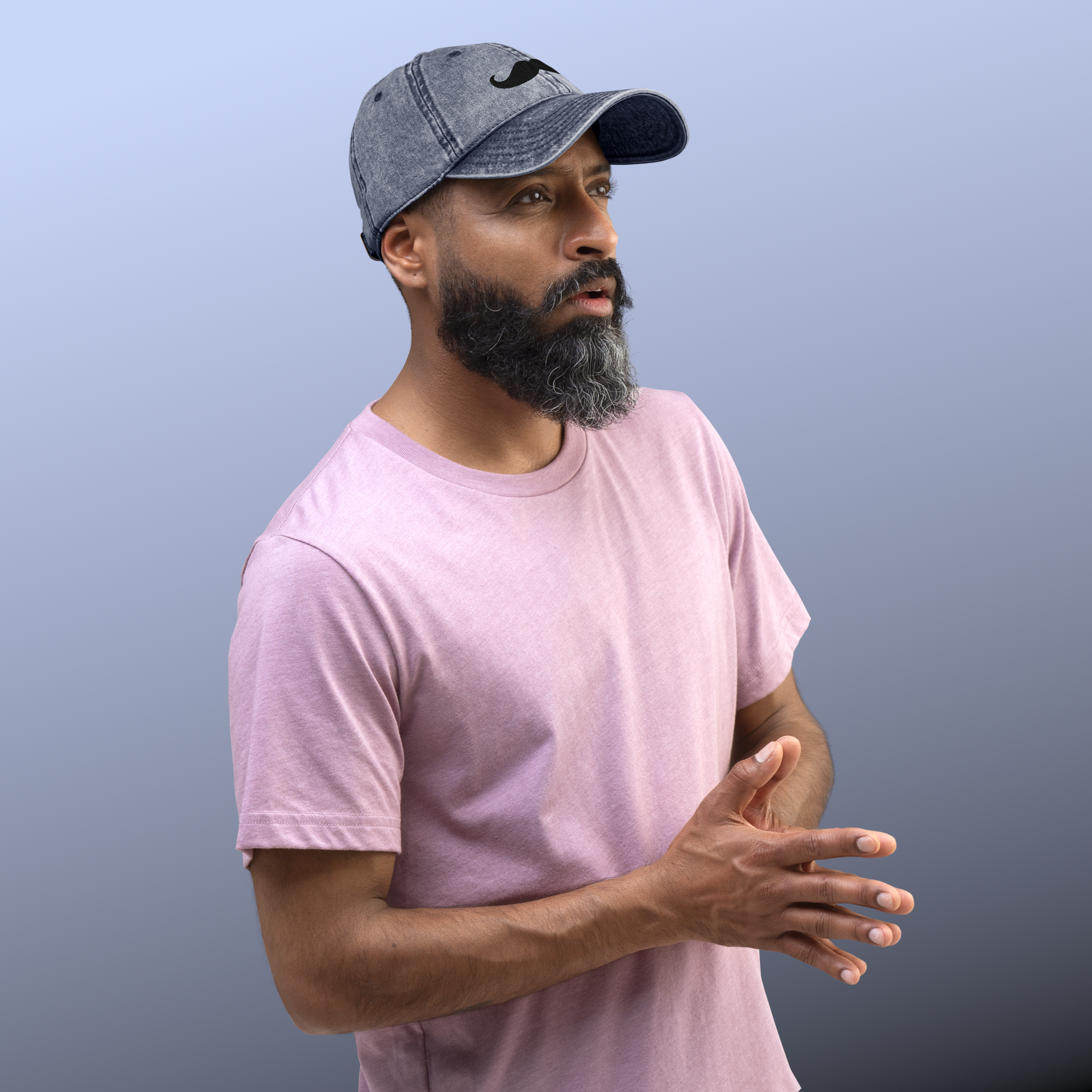 Man wearing a pink t-shirt and denim cap against a gray background