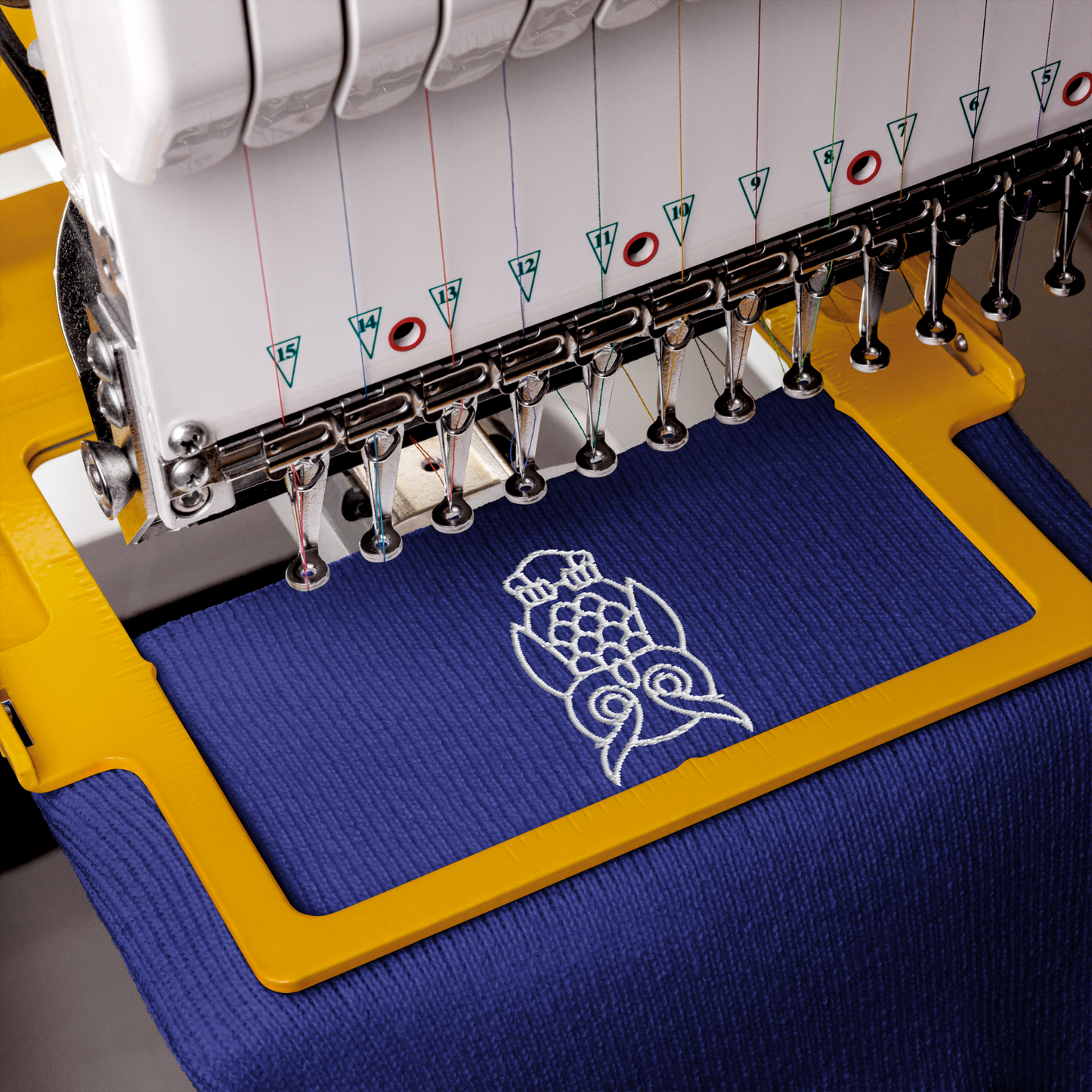 Embroidery machine with a blue hoop and white embroidery design of a owl.