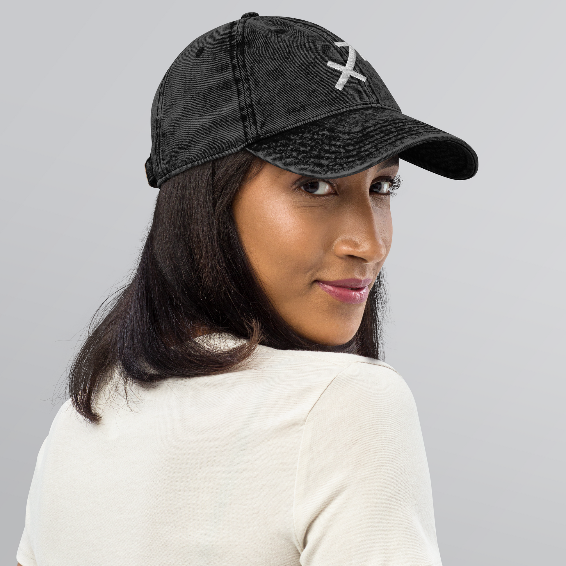 Woman wearing a black cap with a Sagittarius logo on a gray background