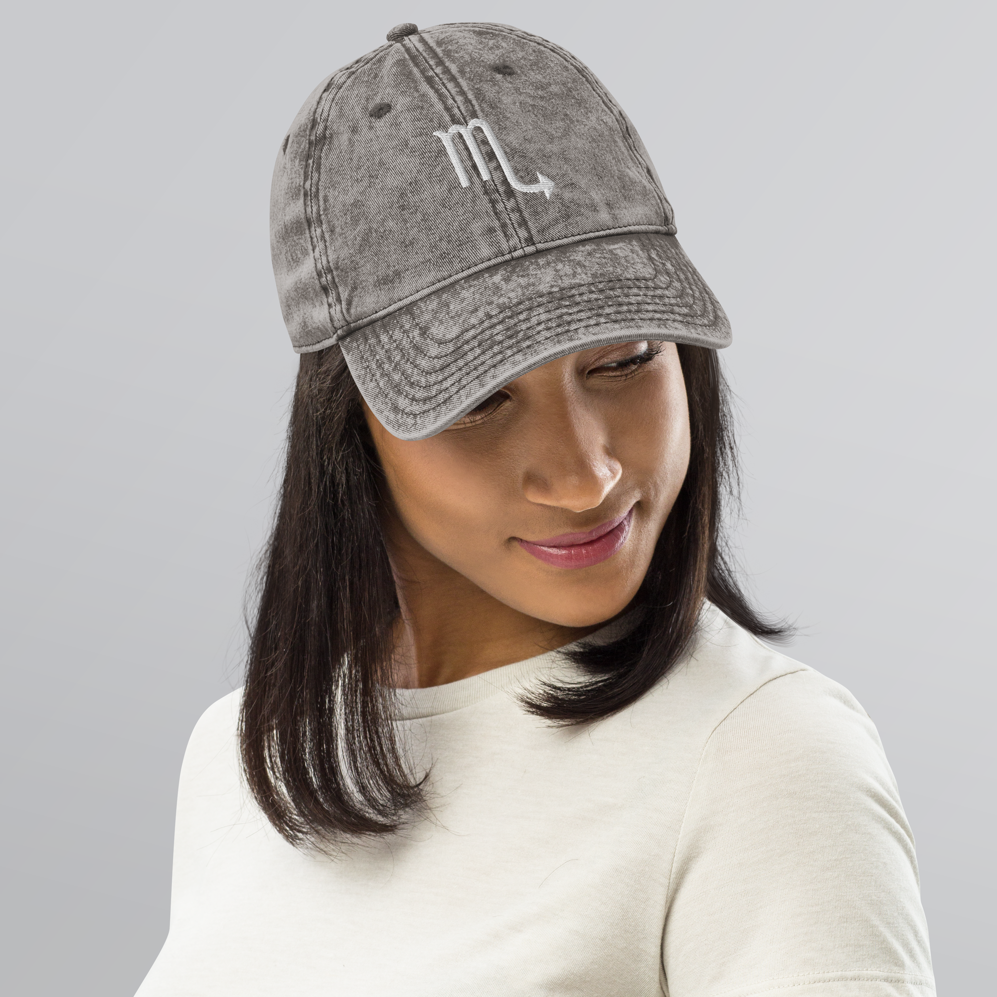 Person wearing a gray baseball cap with a logo on a gray background