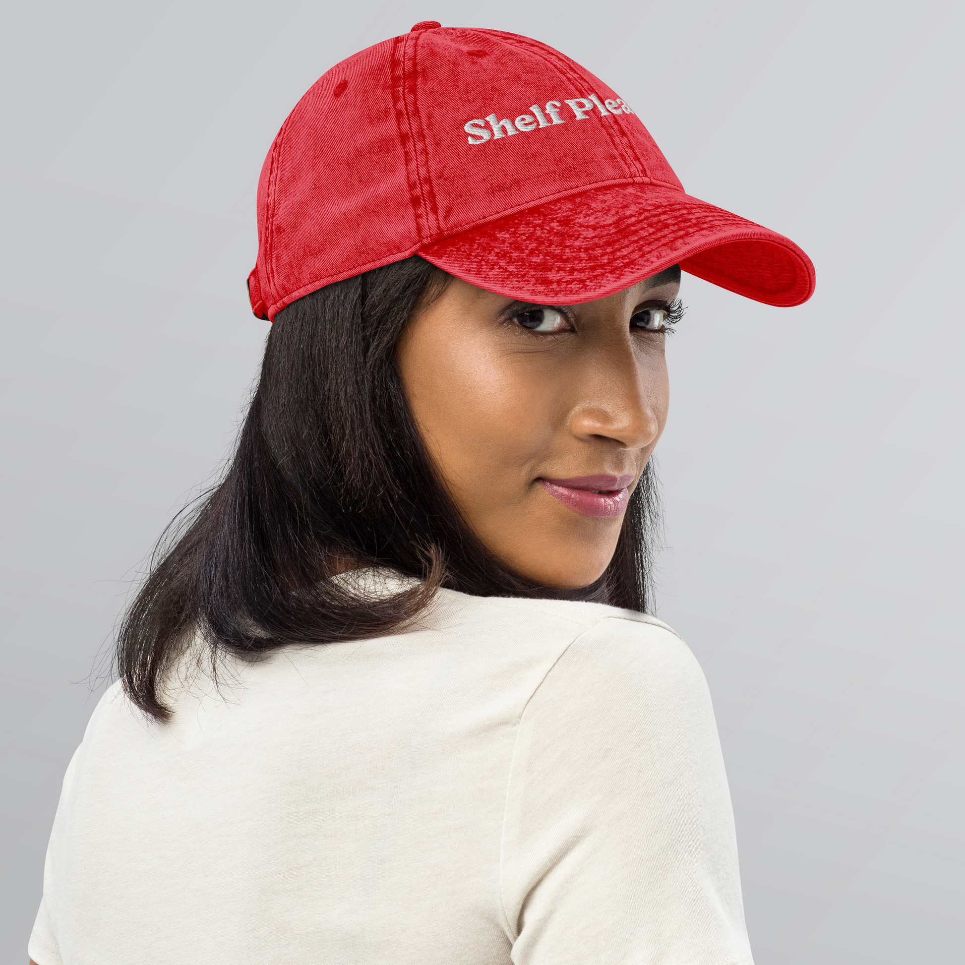 Person wearing a red cap with 'Shelf Plea' text on a gray background