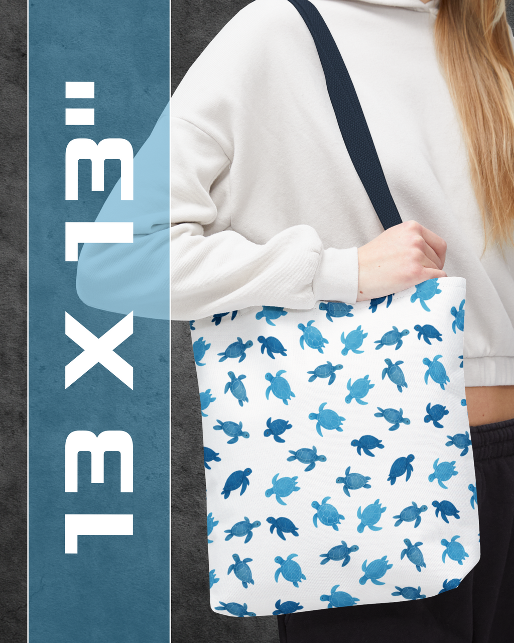 Person holding a white tote bag with blue turtle pattern, with text '13 x 13' on the side.