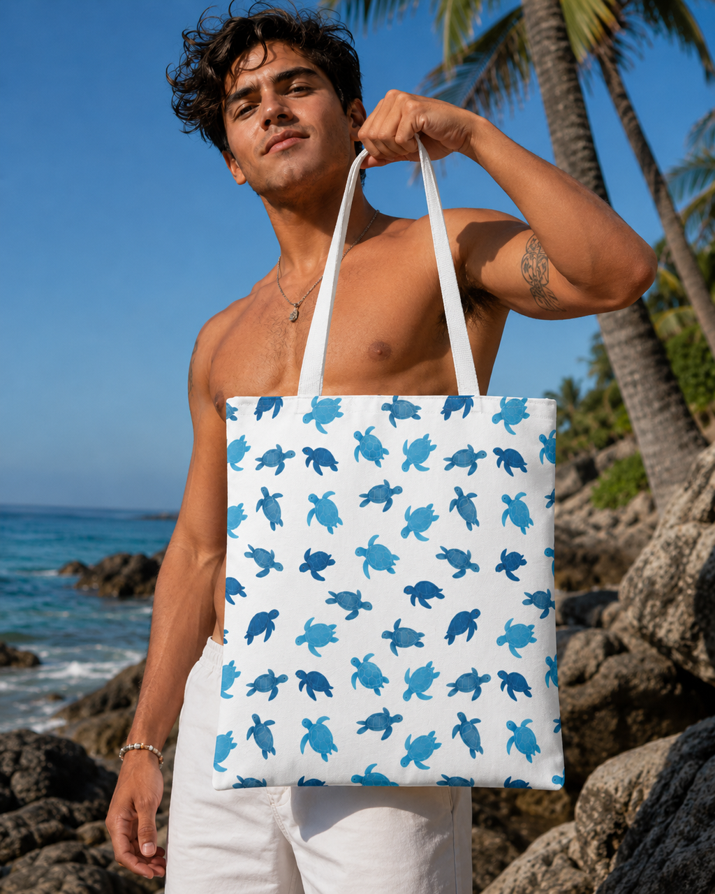 Man holding a tote bag with blue turtle pattern against a beach backdrop