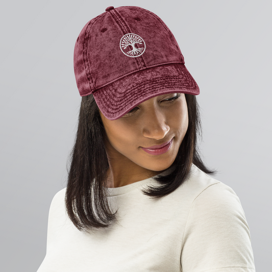 Person wearing a maroon cap with a logo on a gray background