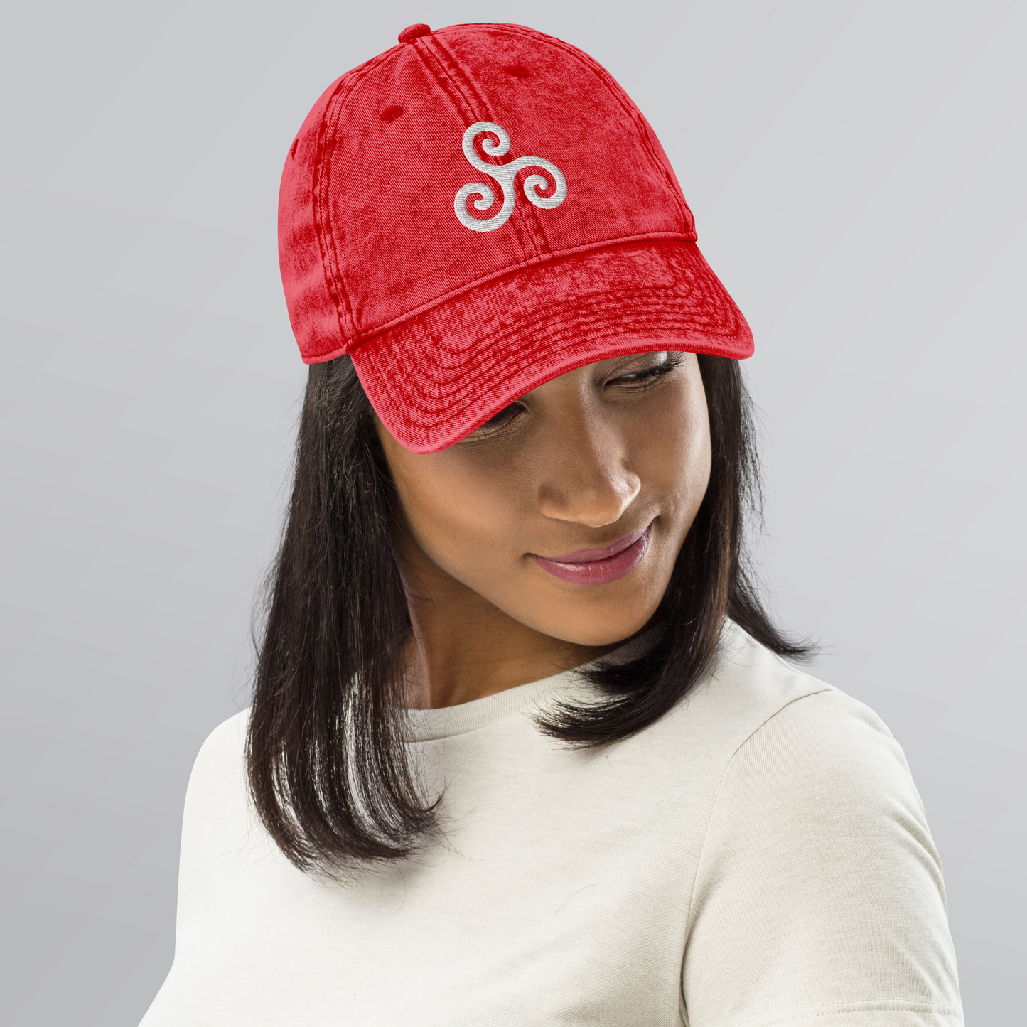 Person wearing a red cap with a white logo on a gray background