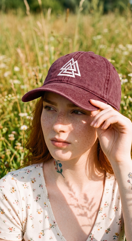 Woman wearing a maroon cap with a white triangle design in a field.
