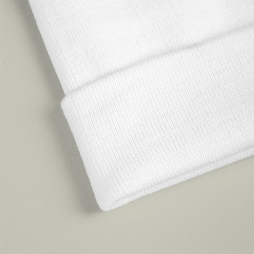 Close-up of a white knit beanie on a light gray background